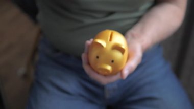 Yaşlı bir adamın eli, bankada tasarruf etmek için kumbaraya bozuk para atıyor. Ağır çekim. Finans kavramı.