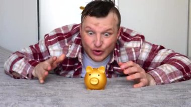 Birçok altın para, mutlu ve gülümseyen bir adamın üzerine ağır çekimde düşer. Altın kumbaralı, bozuk paralı..