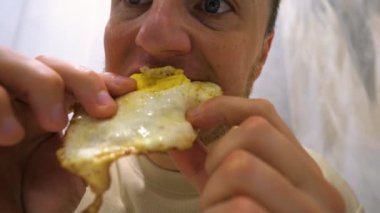 Genç bir adam akşam yemeğinde elleriyle omlet yer, yakın plan. Evde ev yemeği var..