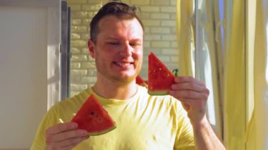 Ellerinde karpuz dilimleri olan neşeli bir adam. Olgun karpuz ye. Yavaş çekim.