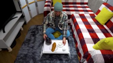  Genç ve şık bir adam bir dairenin oturma odasında otururken fincana kahve dolduruyor. Evde sade kahve iç. Yavaş çekim.