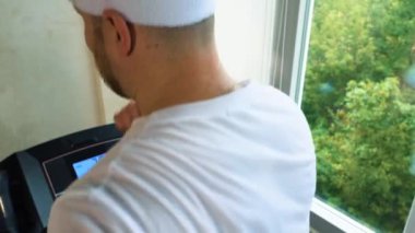 Adam spor salonunda kardiyo çalışması yapıyor, koşu bandında yürüyor ve su içiyor. Yavaş çekim.