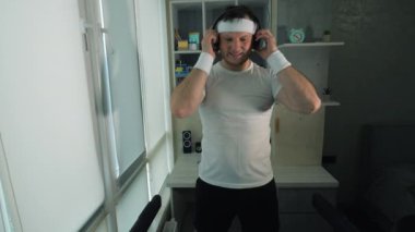 Müzik kulaklıklı bir sporcu, koşu bandında, ağır çekimde. Simülatörde kardiyo eğitimi.