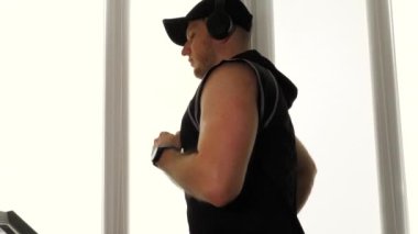  Koşu bandında müzik kulaklığı takan genç bir sporcu. Koşu bandı simülatöründe kardiyo eğitimi.