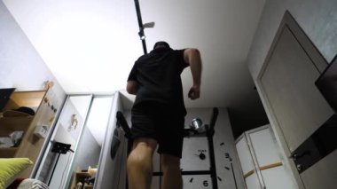 Spor üniformalı bir adam evdeki koşu bandında koşuyor. Kardiyo eğitimi yürüyüşü. Yavaş çekim