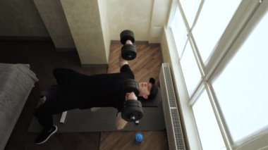  Evdeki spor salonunda aptal göğüs presi. Göğüs kaslarını çalıştıran genç bir adam. Ağır çekim. Üst görünüm.
