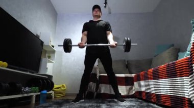 Halteri kol kaslarının üzerine kaldırıyorum. Sporcu evdeki bir dairede antrenman yapıyor. Kollarını halterle sallıyorsun. Yavaş çekim