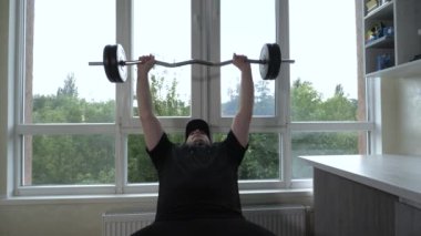 Antrenman sırasında bir bankta yatarken erkek göğüs kaslarını bir bıçakla pompalamak. Genç atlet omuzlarını çalıştırır. Yavaş çekim.