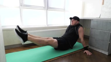 Fitness paspası üzerinde bacak makası egzersizi. Genç aktif bir atlet egzersiz yapıyor ve bacaklarını pompalıyor. Ağır çekim. Evde egzersiz yap..