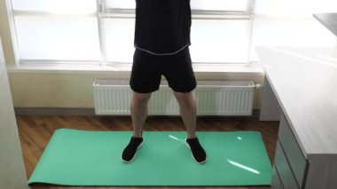 Eğitimde karın kaslarınızı şişirin, dizinizi vücudunuza doğru bükerek bacaklarınızı kaldırın. Evde spor salonunun paspası üzerinde çalışıyorum. Yavaş çekim.