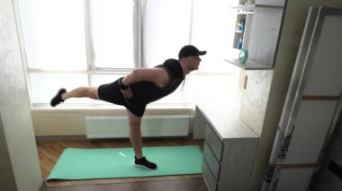 Spor salıncak, bacaklar yukarı, gövde eğik. Spor salonundaki spor salonunun paspasında. Kardiyo eğitimi alan genç bir adam. Yavaş çekim