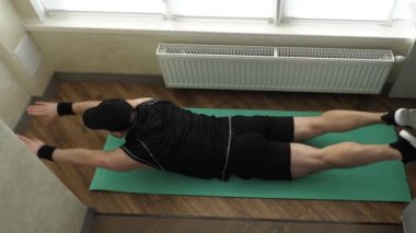 Ev antrenmanı. Yerde yatarken sırt kaslarınızı esnetin. Sırtını güçlendirmek için egzersiz yap. Genç sporcu evde spor minderinde antrenman yapıyor. Yavaş çekim