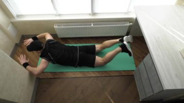 Ev antrenmanı. Sırtınızı ve karın kaslarınızı güçlendirin. Bacaklarını kaldırma egzersizi yap. Genç sporcu evde spor minderinde antrenman yapıyor. Yavaş çekim