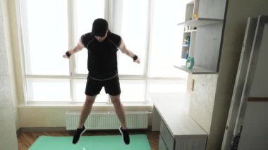 Yoğun kardiyo ev fitness egzersizleri, bacak egzersizleri ve zıplama egzersizleri. Adam yağ yakma egzersizi yapıyor. Yavaş çekim.