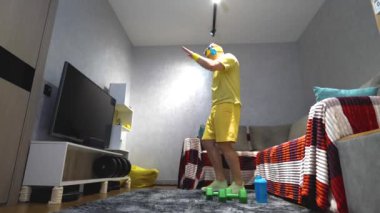 Sportif bir adam evde müzik dinlerken kulaklıkla dans ediyor. Ağır çekim. Genç bir sporcu evde eğleniyor..