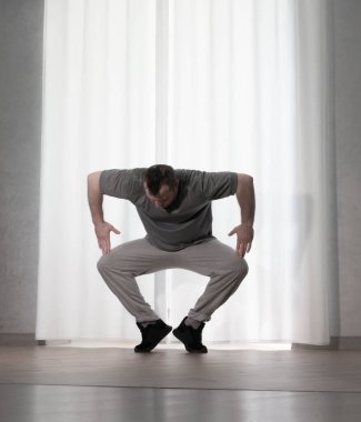 Hareketli dans, hip-hop tarzı giyinmiş bir adamın pozu. Antrenmandaki spor dansçısı poz veriyor. Evde dans eğitimi..
