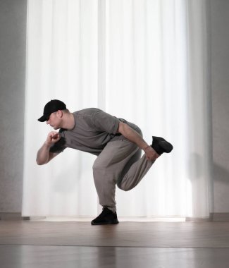 Hareketli dans, hip-hop tarzı giyinmiş bir adamın pozu. Antrenmandaki spor dansçısı poz veriyor. Evde dans eğitimi..