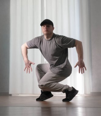 Hareketli dans, hip-hop tarzı giyinmiş bir adamın pozu. Antrenmandaki spor dansçısı poz veriyor. Evde dans eğitimi..