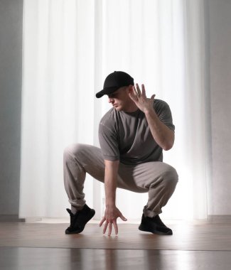 Hareketli dans, hip-hop tarzı giyinmiş bir adamın pozu. Antrenmandaki spor dansçısı poz veriyor. Evde dans eğitimi..