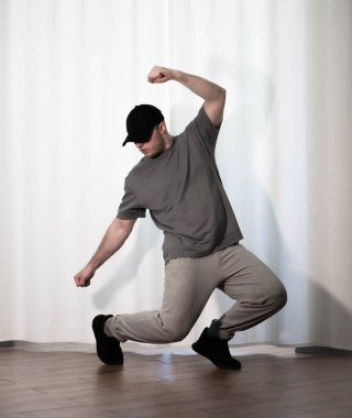Hareketli dans, hip-hop tarzı giyinmiş bir adamın pozu. Antrenmandaki spor dansçısı poz veriyor. Evde dans eğitimi..