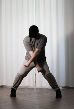 Hareketli dans, hip-hop tarzı giyinmiş bir adamın pozu. Antrenmandaki spor dansçısı poz veriyor. Evde dans eğitimi..