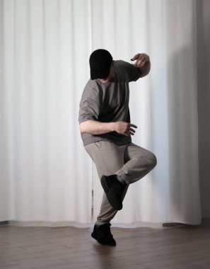 Hareketli dans, hip-hop tarzı giyinmiş bir adamın pozu. Antrenmandaki spor dansçısı poz veriyor. Evde dans eğitimi..
