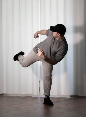 Hareketli dans, hip-hop tarzı giyinmiş bir adamın pozu. Antrenmandaki spor dansçısı poz veriyor. Evde dans eğitimi..