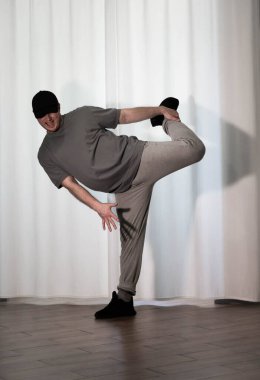 Hareketli dans, hip-hop tarzı giyinmiş bir adamın pozu. Antrenmandaki spor dansçısı poz veriyor. Evde dans eğitimi..