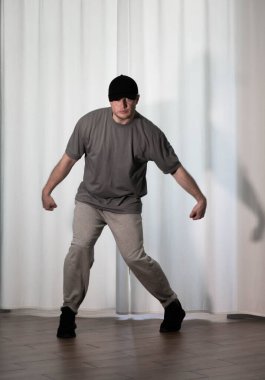 Hareketli dans, hip-hop tarzı giyinmiş bir adamın pozu. Antrenmandaki spor dansçısı poz veriyor. Evde dans eğitimi..
