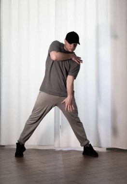 Hareketli dans, hip-hop tarzı giyinmiş bir adamın pozu. Antrenmandaki spor dansçısı poz veriyor. Evde dans eğitimi..