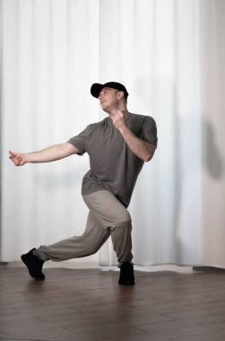 Hareketli dans, hip-hop tarzı giyinmiş bir adamın pozu. Antrenmandaki spor dansçısı poz veriyor. Evde dans eğitimi..