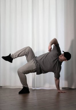 Hareketli dans, hip-hop tarzı giyinmiş bir adamın pozu. Antrenmandaki spor dansçısı poz veriyor. Evde dans eğitimi..