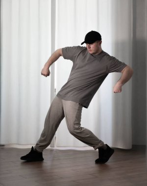 Hareketli dans, hip-hop tarzı giyinmiş bir adamın pozu. Antrenmandaki spor dansçısı poz veriyor. Evde dans eğitimi..
