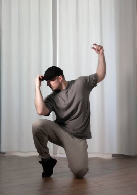 Hareketli dans, hip-hop tarzı giyinmiş bir adamın pozu. Antrenmandaki spor dansçısı poz veriyor. Evde dans eğitimi..