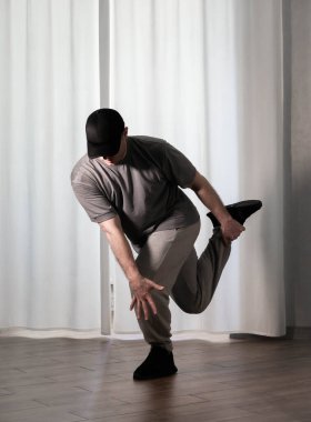 Hareketli dans, hip-hop tarzı giyinmiş bir adamın pozu. Antrenmandaki spor dansçısı poz veriyor. Evde dans eğitimi..