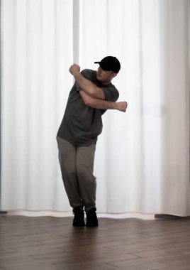 Hareketli dans, hip-hop tarzı giyinmiş bir adamın pozu. Antrenmandaki spor dansçısı poz veriyor. Evde dans eğitimi..