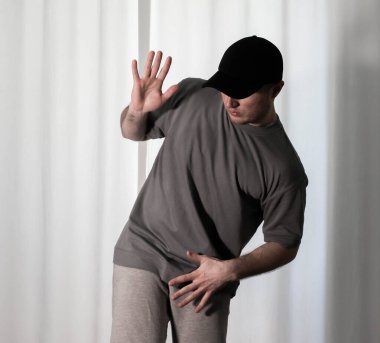 Hareketli dans, hip-hop tarzı giyinmiş bir adamın pozu. Antrenmandaki spor dansçısı poz veriyor. Evde dans eğitimi..