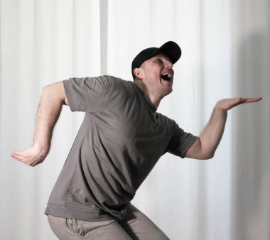 Hareketli dans, hip-hop tarzı giyinmiş bir adamın pozu. Antrenmandaki spor dansçısı poz veriyor. Evde dans eğitimi..