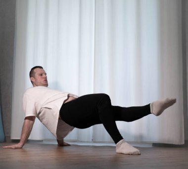 Evde yoga pozu egzersizi. Kolları ve bacaklarıyla spor egzersizleri yapan bir adam. Erkek sporcu geriniyor..