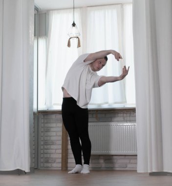 Evde yoga pozu egzersizi. Kolları ve bacaklarıyla spor egzersizleri yapan bir adam. Erkek sporcu geriniyor..