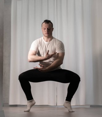 Yoga pozisyonunda ev çalışması. Bir adam kolları ve bacaklarıyla spor dansı egzersizleri yapıyor. Pilates esneme