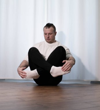 Evde yoga pozu egzersizi. Kolları ve bacaklarıyla spor egzersizleri yapan bir adam. Erkek sporcu geriniyor..