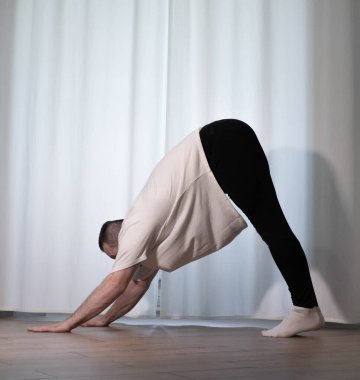 Evde yoga pozu egzersizi. Kolları ve bacaklarıyla spor egzersizleri yapan bir adam. Erkek sporcu geriniyor..