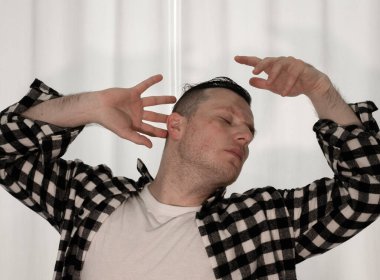 Beyaz arka planda dans eden genç adam. Ekose gömlekle modern dans. Spor plastik hareketler kollar, bacaklar ve gövde.