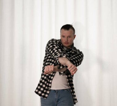 Beyaz arka planda dans eden genç adam. Ekose gömlekle modern dans. Spor plastik hareketler kollar, bacaklar ve gövde.