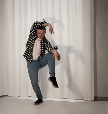Beyaz arka planda dans eden genç adam. Ekose gömlekle modern dans. Spor plastik hareketler kollar, bacaklar ve gövde.