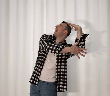 Beyaz arka planda dans eden genç adam. Ekose gömlekle modern dans. Spor plastik hareketler kollar, bacaklar ve gövde.