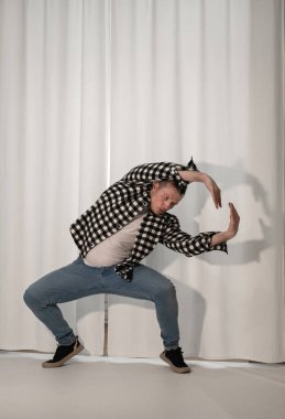 Beyaz arka planda dans eden genç adam. Ekose gömlekle modern dans. Spor plastik hareketler kollar, bacaklar ve gövde.