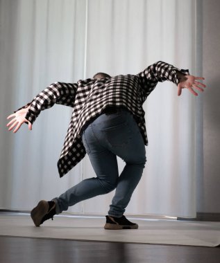 Beyaz arka planda dans eden genç adam. Ekose gömlekle modern dans. Spor plastik hareketler kollar, bacaklar ve gövde.