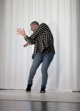 Beyaz arka planda dans eden genç adam. Ekose gömlekle modern dans. Spor plastik hareketler kollar, bacaklar ve gövde.